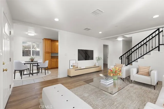 a living room with furniture and a dining table with wooden floor