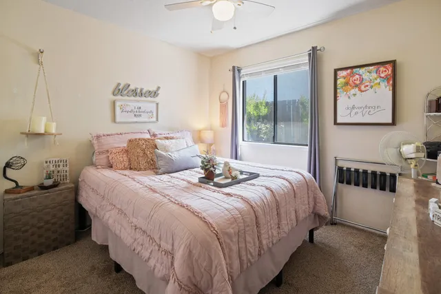 a bedroom with a bed a window and potted plant on the dresser