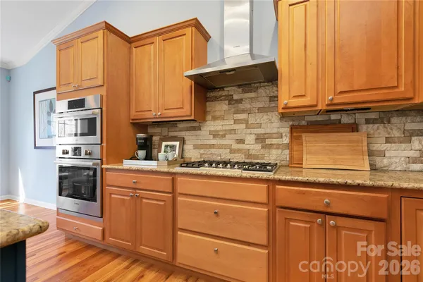 a kitchen with granite countertop cabinets stainless steel appliances a sink and wooden floor
