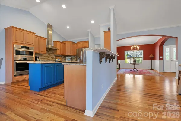 a view of a kitchen with kitchen island a stove wooden floors and wooden cabinets