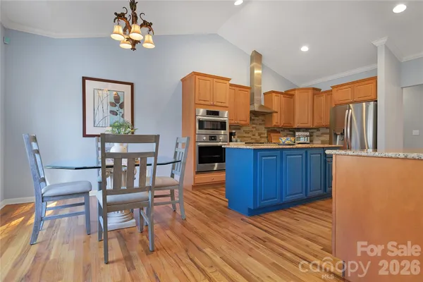 a kitchen with stainless steel appliances granite countertop a table chairs and a wooden floors