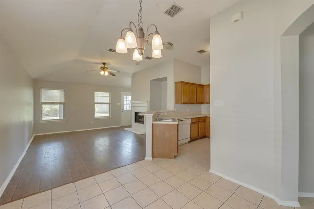 an empty room with wooden floor and kitchen view