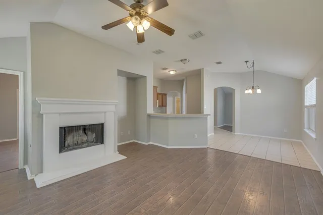 a view of an empty room with wooden floor and a fireplace