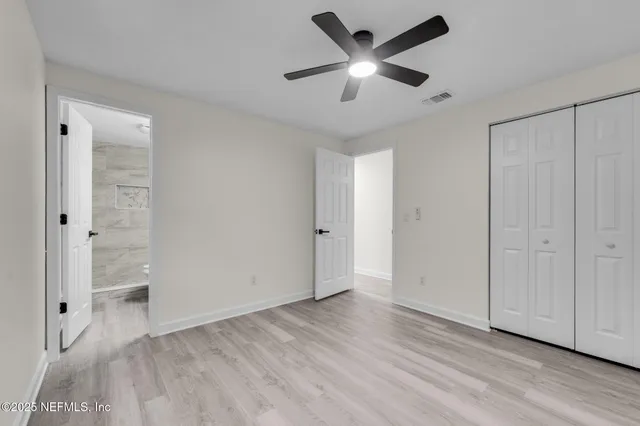 an empty room with wooden floor and a ceiling fan