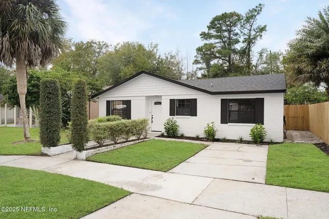 a front view of a house with a yard and potted plants