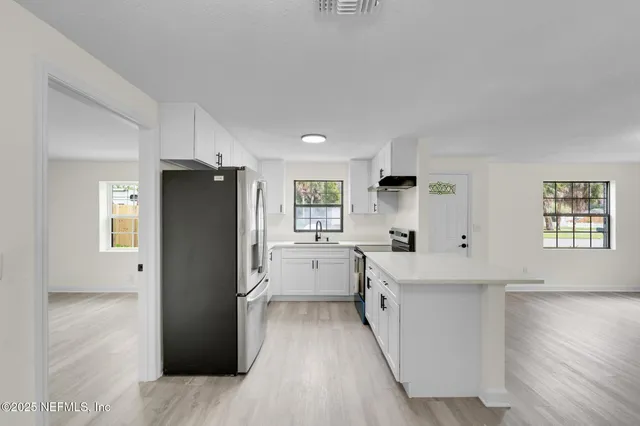 a kitchen with a refrigerator a sink and dishwasher with wooden floor