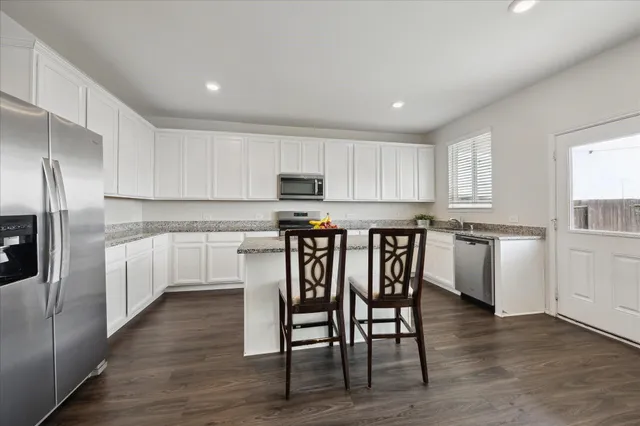 a kitchen with granite countertop white cabinets and stainless steel appliances