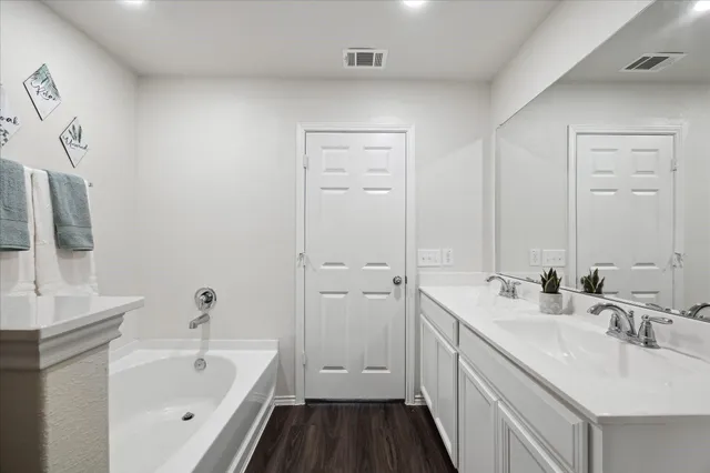 a bathroom with a double vanity sink a mirror and a bathtub