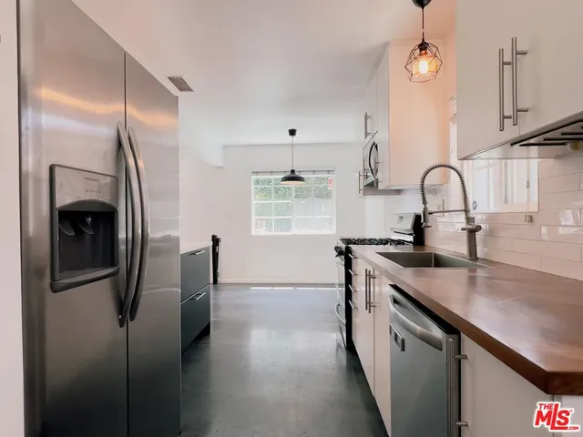 a kitchen with stainless steel appliances granite countertop a sink a stove and a refrigerator