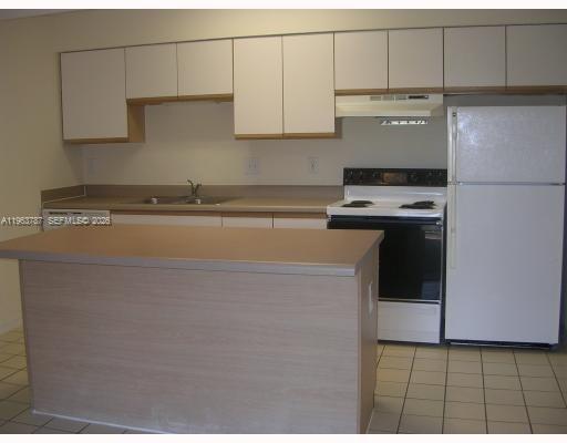 4055 West McNab Road, Unit H303 Pompano Beach, FL 33069 - Photo 3 of 12 a kitchen with cabinets and white appliances