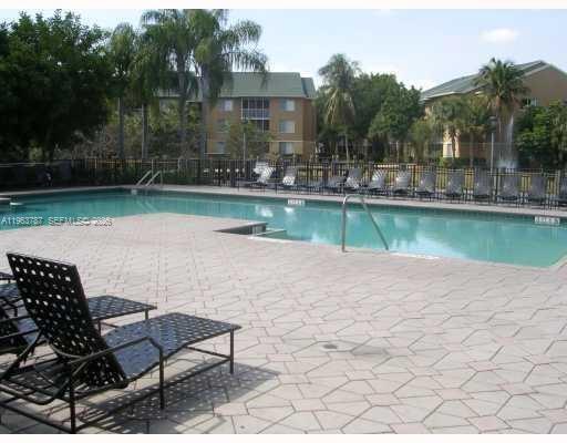 4055 West McNab Road, Unit H303 Pompano Beach, FL 33069 - Photo 9 of 12 a swimming pool with outdoor seating and yard