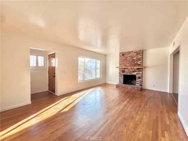 an empty room with wooden floor and fireplace