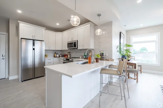 a kitchen with stainless steel appliances kitchen island a table chairs refrigerator and microwave