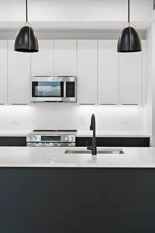 a kitchen with stainless steel appliances a sink a microwave a stove and a refrigerator