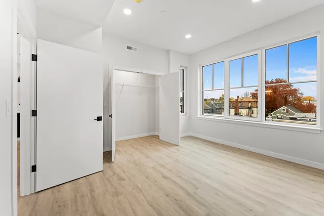 a view of an empty room with a window and wooden floor