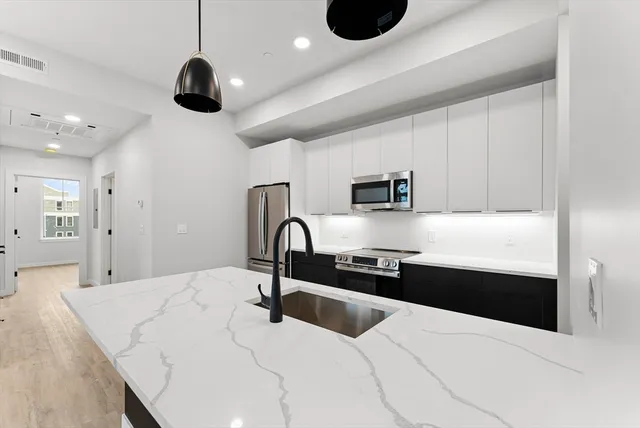 a kitchen with a sink stainless steel appliances and white cabinets