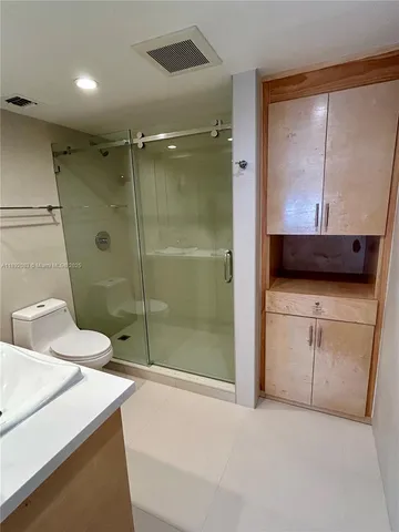 a bathroom with a granite countertop sink a toilet a mirror and shower