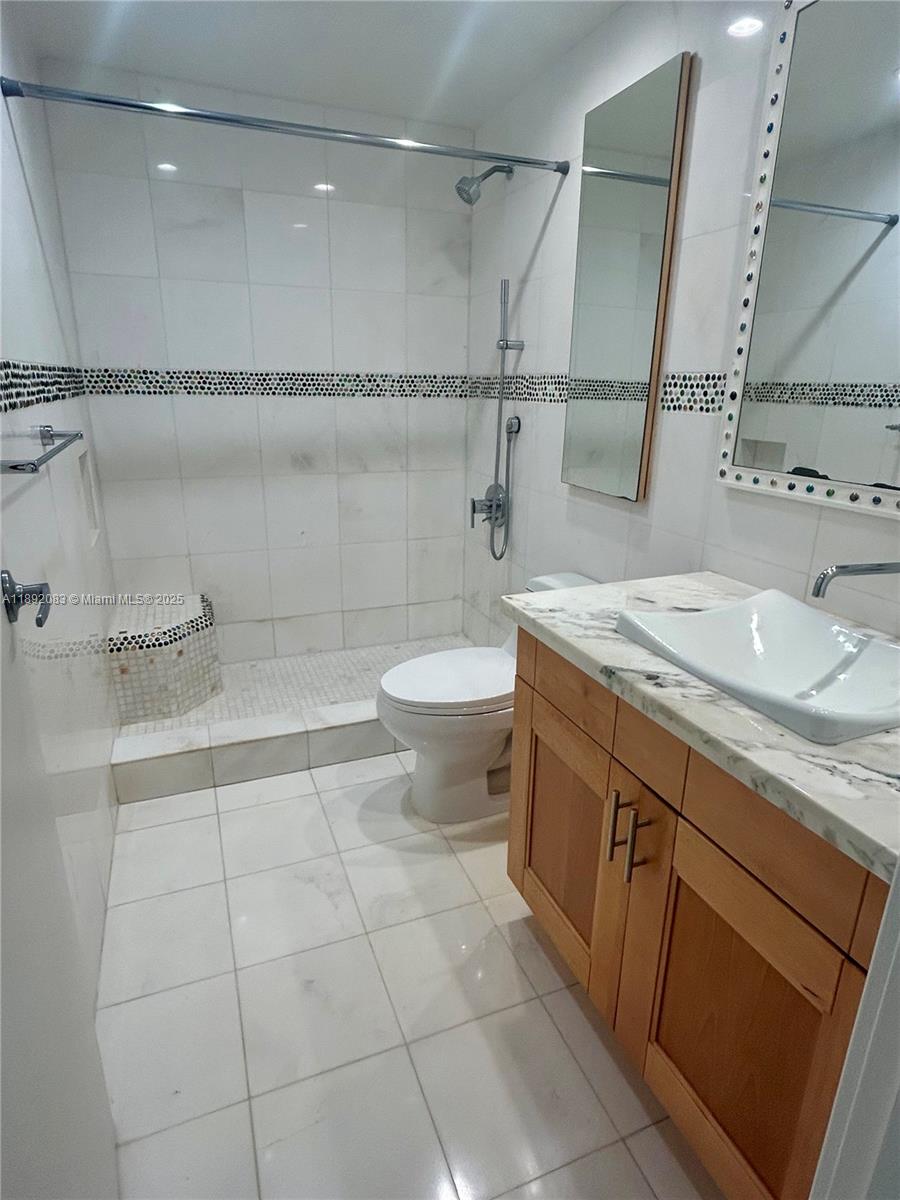 5415 Collins Avenue, Unit 302 Miami Beach, FL 33140 - Photo 19 of 33 a bathroom with a granite countertop sink a toilet a mirror and shower