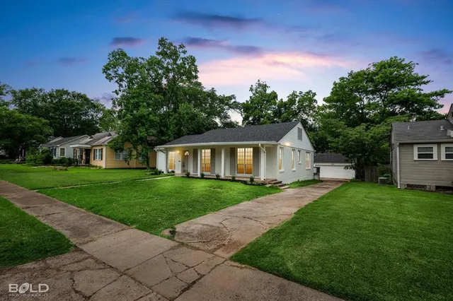 a front view of a house with a garden and trees
