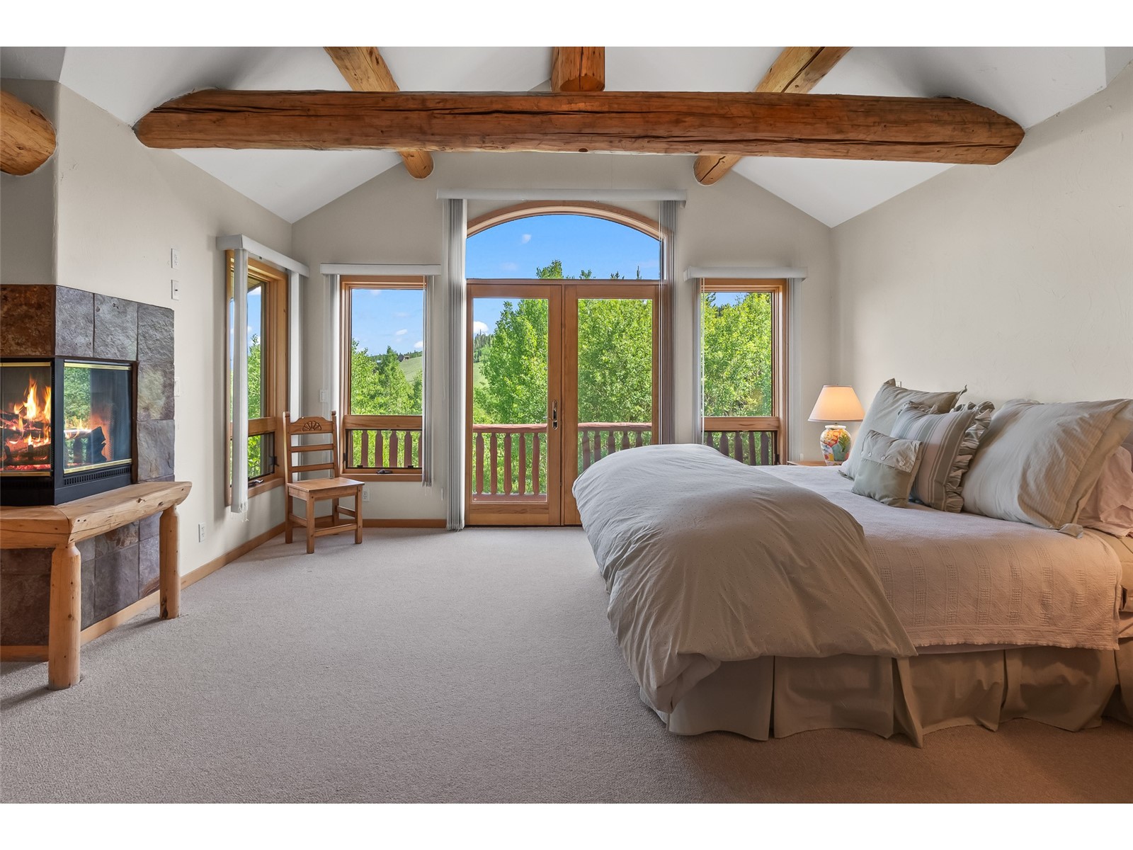 1746 South Ruby Road Silverthorne, CO 80498 - Photo 32 of 50 Carpeted bedroom with beam ceiling, a tiled fireplace, access to outside, and multiple windows