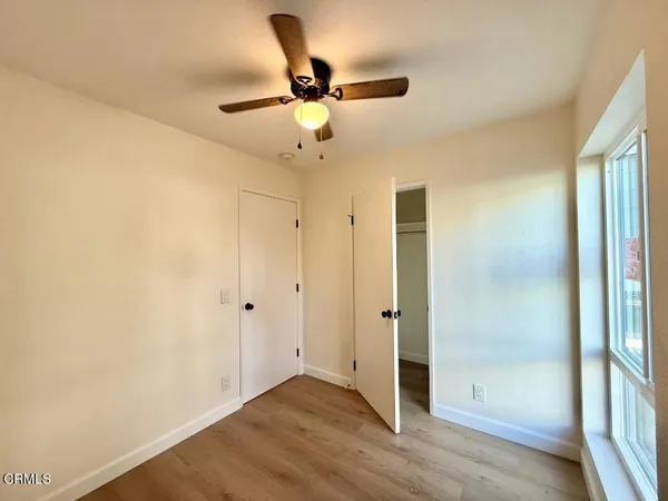 a view of empty room with wooden floor and fan