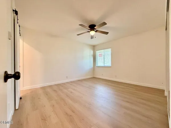 a view of empty room with wooden floor and ceiling fan