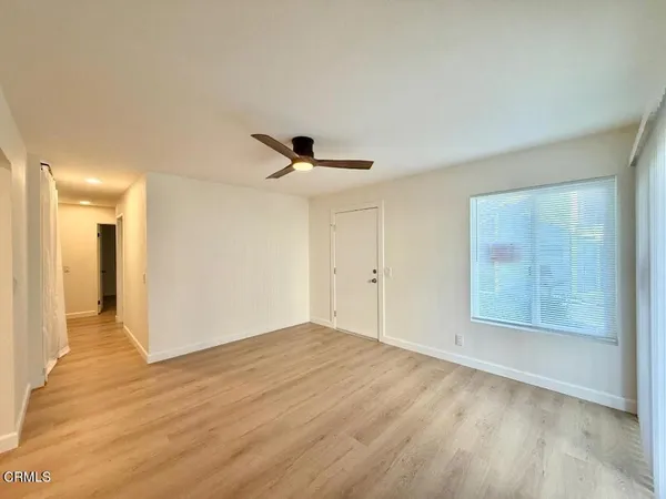 a view of empty room with wooden floor and fan