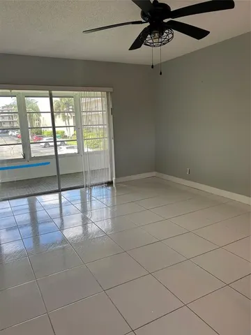 an empty room with windows and ceiling fan