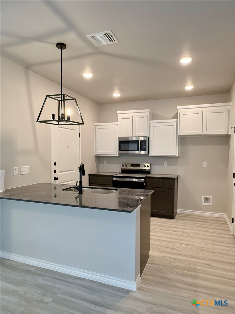 110 Leon Lane Copperas Cove, TX 76522 - Photo 6 of 20 a kitchen with stainless steel appliances granite countertop a sink a stove and a wooden floors