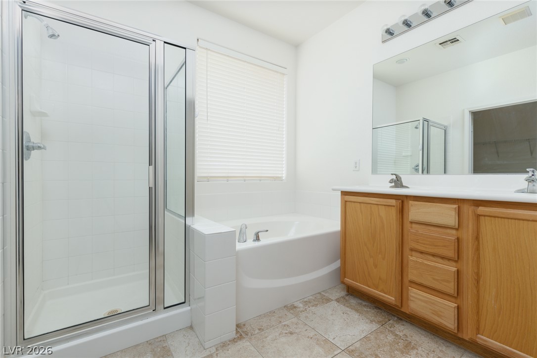 787 Rise Canyon Drive Henderson, NV 89052 - Photo 10 of 22 A well-lit bathroom features a glass-enclosed shower, separate soaking tub, and a dual vanity with ample counter space.