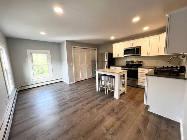 a kitchen with microwave a stove top oven and cabinets with wooden floor