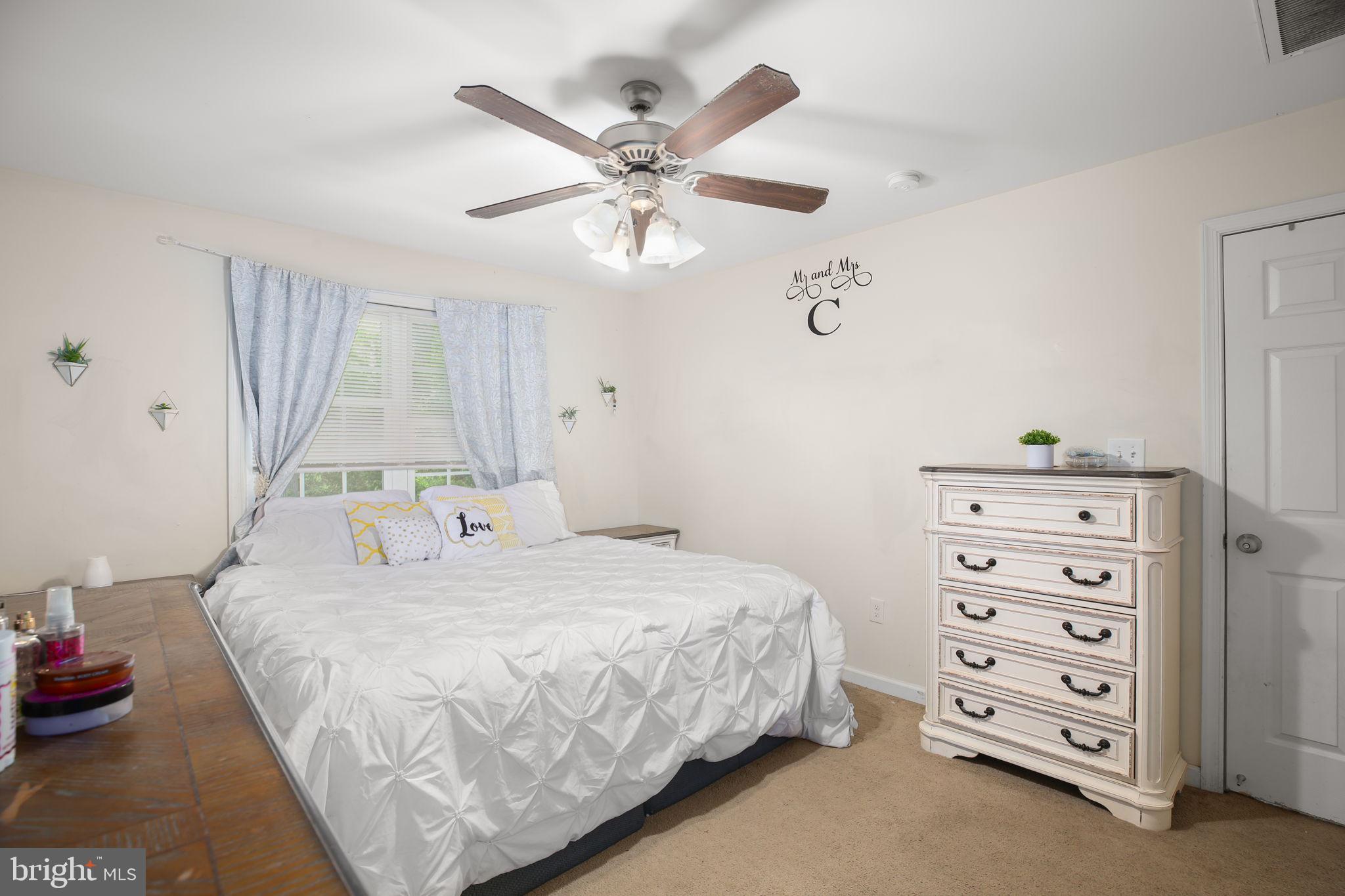 317 12th Street Colonial Beach, VA 22443 - Photo 14 of 28 a bedroom with a bed a chandelier and a dresser