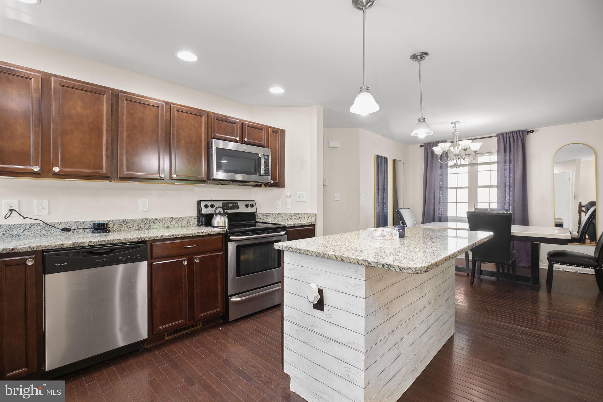 317 12th Street Colonial Beach, VA 22443 - Photo 2 of 28 a open kitchen with stainless steel appliances granite countertop a stove a sink dishwasher a microwave oven and a dining table with wooden floor