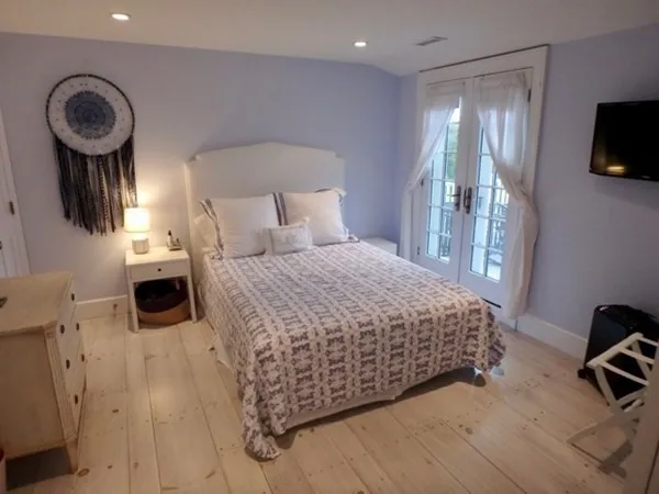 a bedroom with a bed a mirror on dresser and a wooden floor