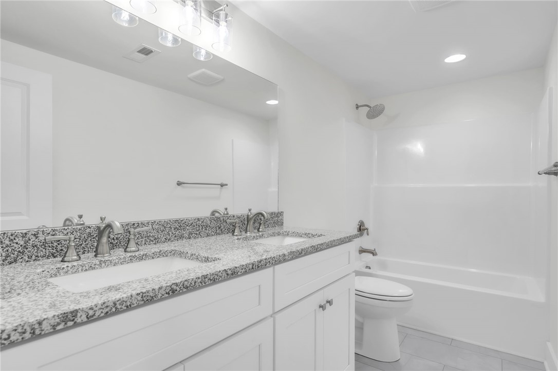 7 Beaverdam Road Williamston, SC 29697 - Photo 26 of 27 Modern bath features a double vanity with granite counters, paired with a clean white tub and shower combination.