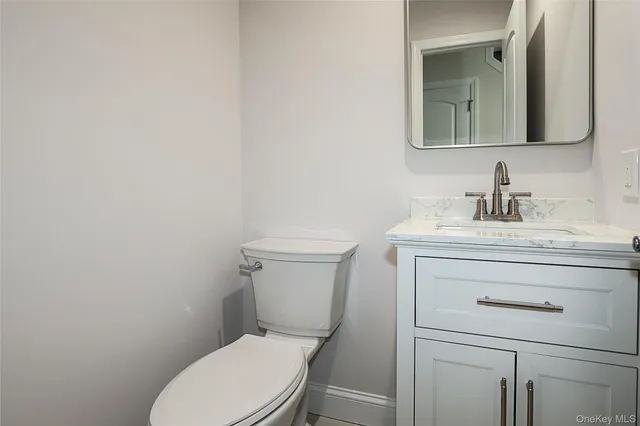 a bathroom with a toilet sink vanity and mirror
