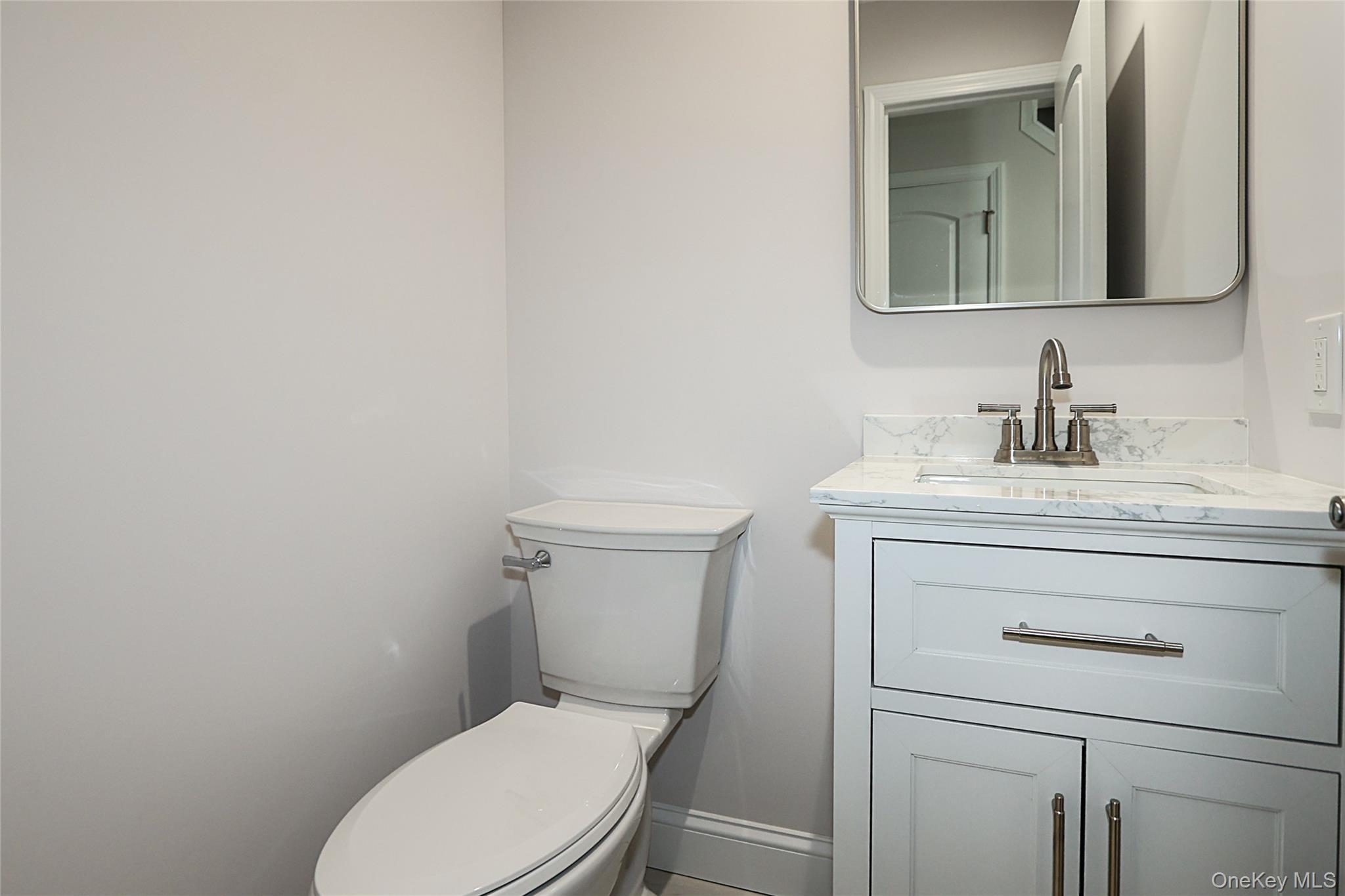 10 Smith Yaphank, NY 11980 - Photo 15 of 26 a bathroom with a toilet sink vanity and mirror