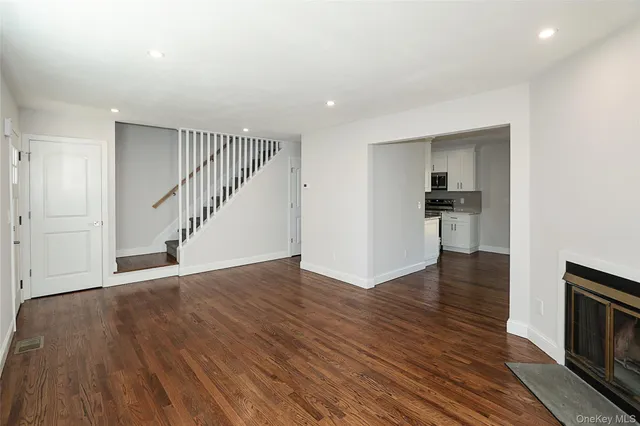 a view of empty room with wooden floor and a fireplace