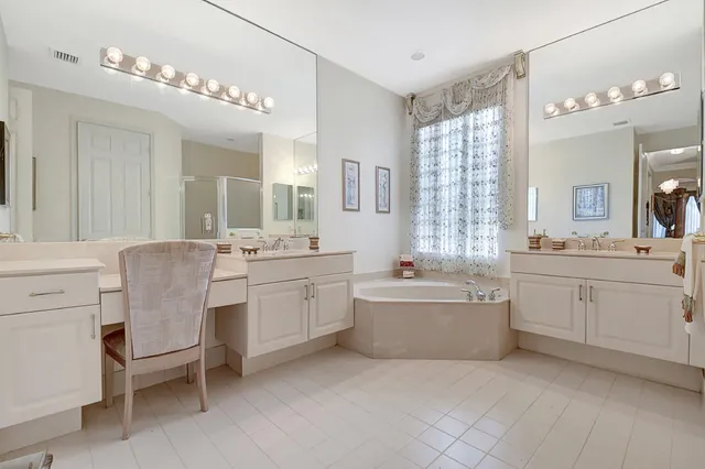 a bathroom with a granite countertop bathtub a sink and a large mirror