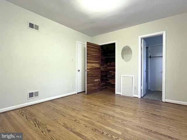 a view of an empty room with wooden floor and closet