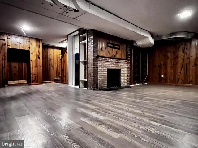 a view of an empty room with wooden floor and a fireplace