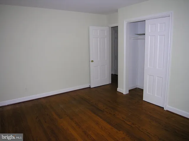 a view of an empty room with wooden floor and closet