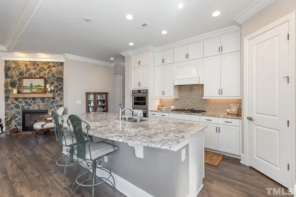 a kitchen with kitchen island granite countertop a sink cabinets and wooden floor