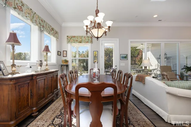 a dining room with wooden floor a chandelier a wooden table and chairs