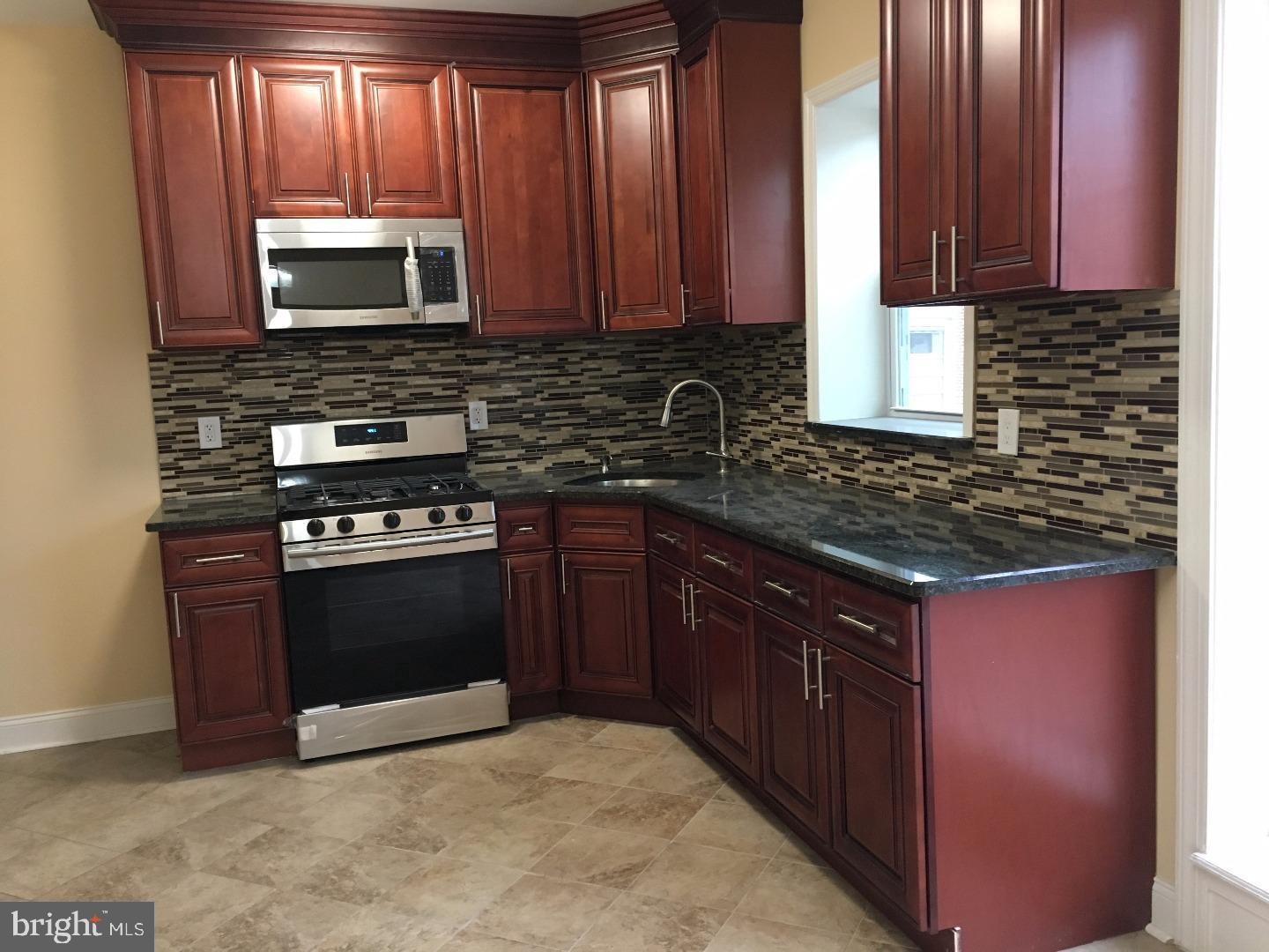a kitchen with stainless steel appliances granite countertop wooden cabinets a stove top oven with a sink and dishwasher