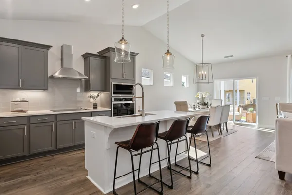 a kitchen with stainless steel appliances kitchen island a table chairs sink and cabinets