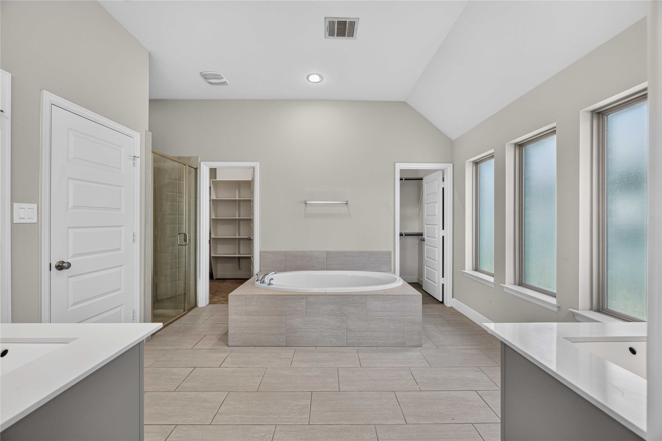 4333 Arbor Crest Lane Manvel, TX 77578 - Photo 18 of 40 This primary bath is a true wellness oasis illuminated by multiple frosted windows, showcasing a deep soaking tub, dual vanities and a glass-enclosed shower.