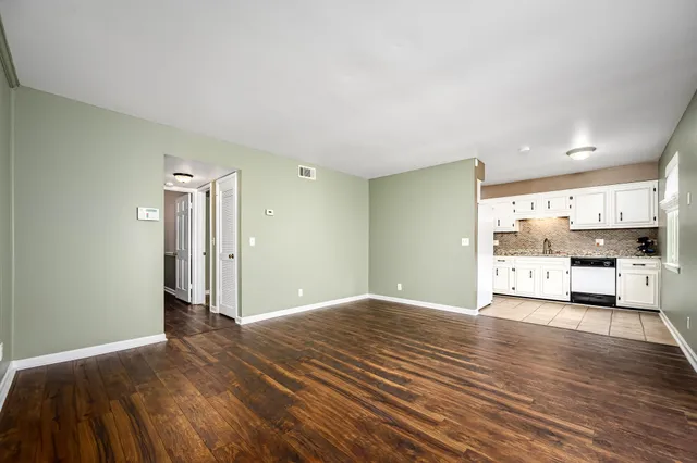 a view of a big room with wooden floor and windows