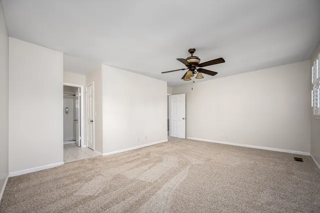 an empty room with a window and a fan