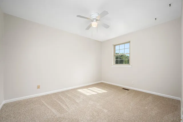 an empty room with a window and a fan
